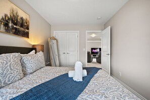 Quarto de hotel com cama, televisão e um quadro na parede.