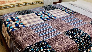 Une chambre à coucher avec un lit en bois, une grande couvre-lit et une fenêtre avec des volets en bois.