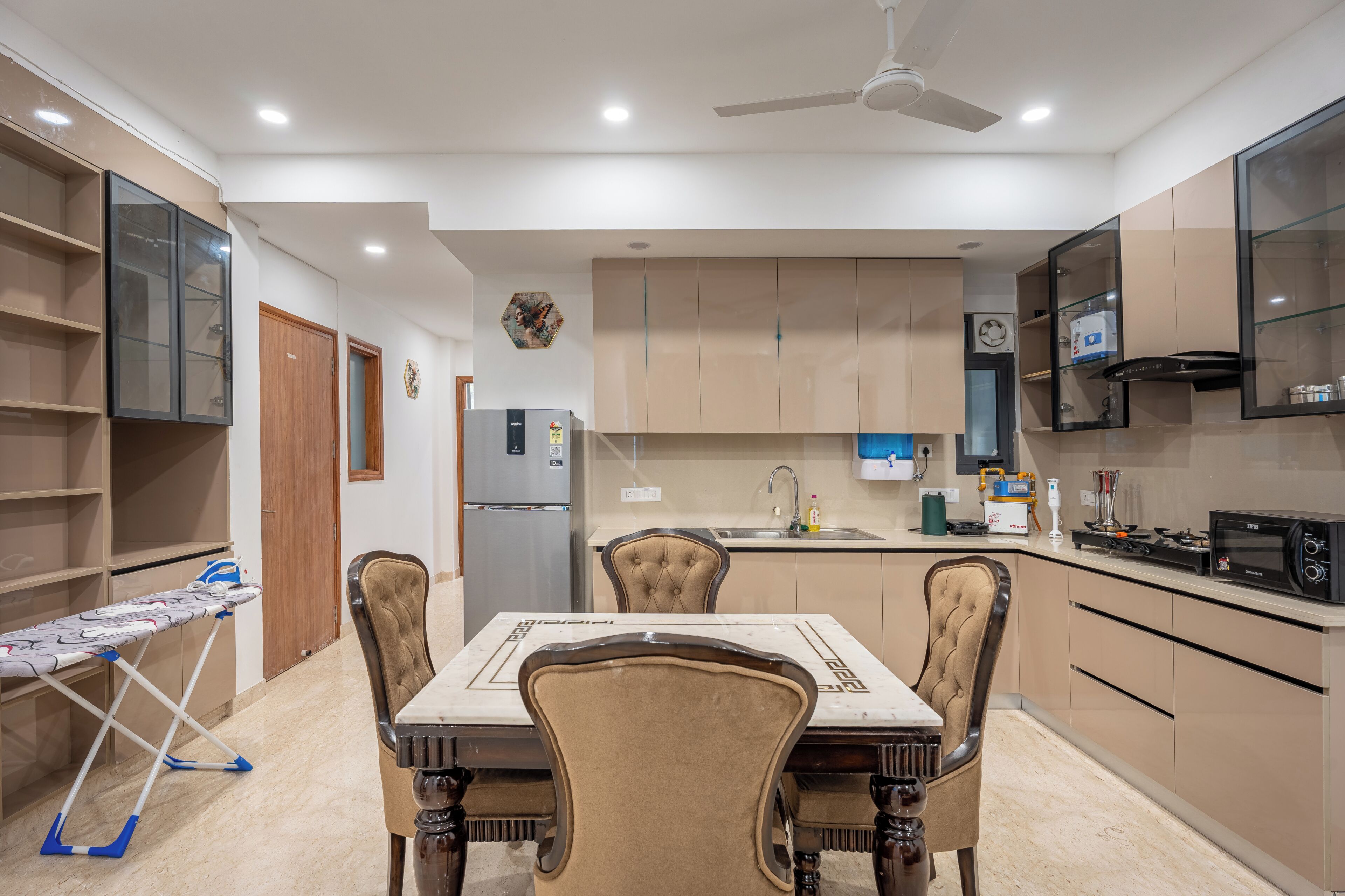 A modern kitchen with a dining area, featuring a built-in microwave, a refrigerator, and a sink.