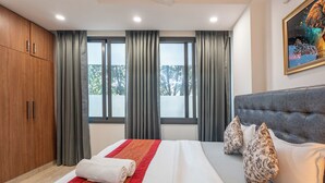Ein Hotelzimmer mit einem großen Bett, grauen Vorhängen, einem grauen Kopfteil und einem Bild an der Wand.