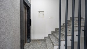 Eine Treppe mit Granitstufen und schwarzen Geländern, die zu einer Tür führt, über der sich ein kleines, weißes Gegensprechanlage befindet.