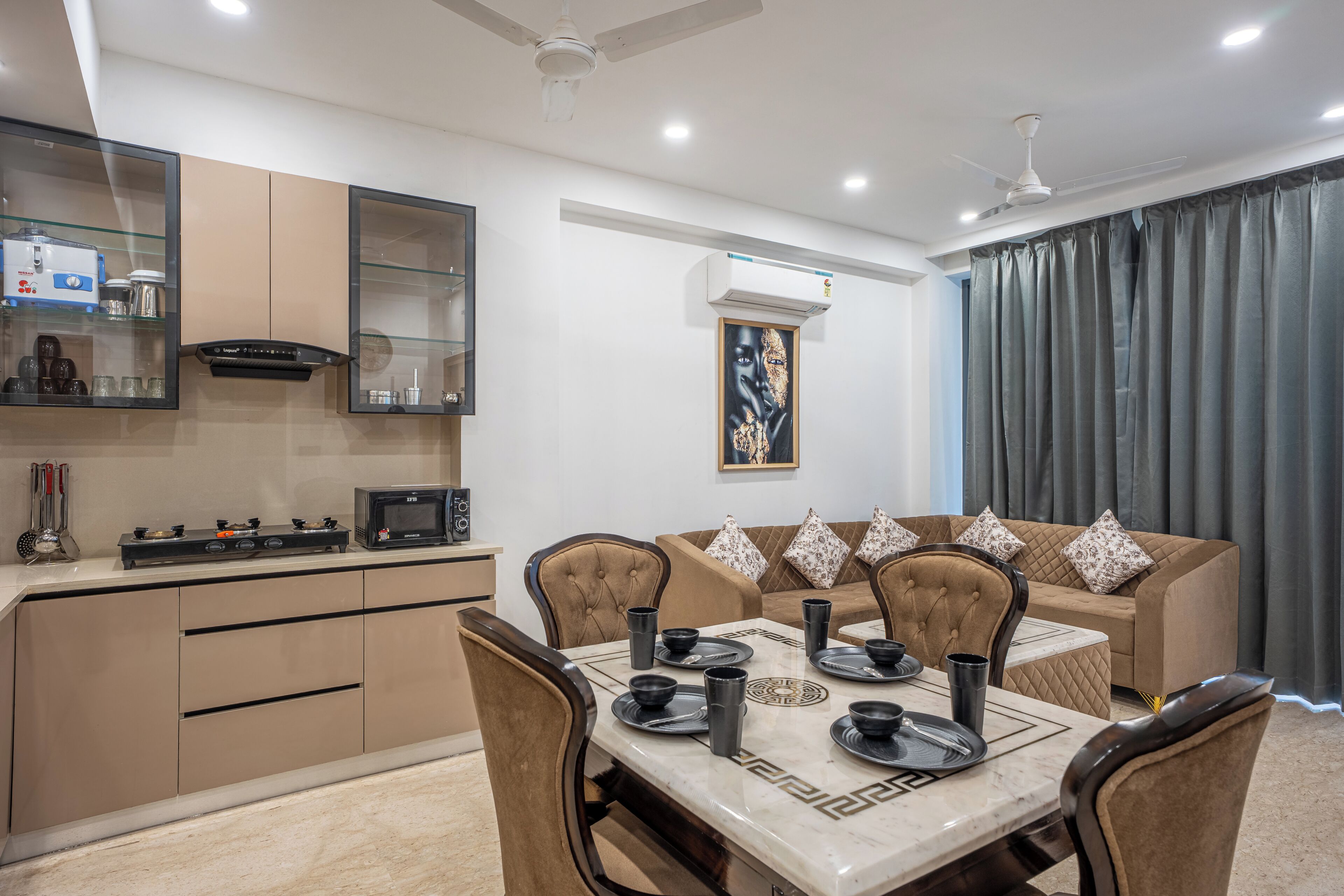 A modern kitchen with a dining area, including a table set for four, a sofa, and a ceiling fan.