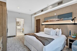 A modern hotel room with a large bed, a mounted TV, a bedside lamp, and a view of the bathroom. - Steps to Gondola • Shared Pool + Mountain Views • Resort Access | Gondola & Gold (Avon)