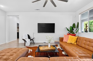 Ein modernes Wohnzimmer mit einer Ledersofa, einem Couchtisch und einem flachbildfernseher an der Wand.
