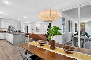 Eine moderne Küche mit weißen Schränken, einer eingebauten Mikrowelle und einem Essbereich mit einem Holztisch und Stühlen.