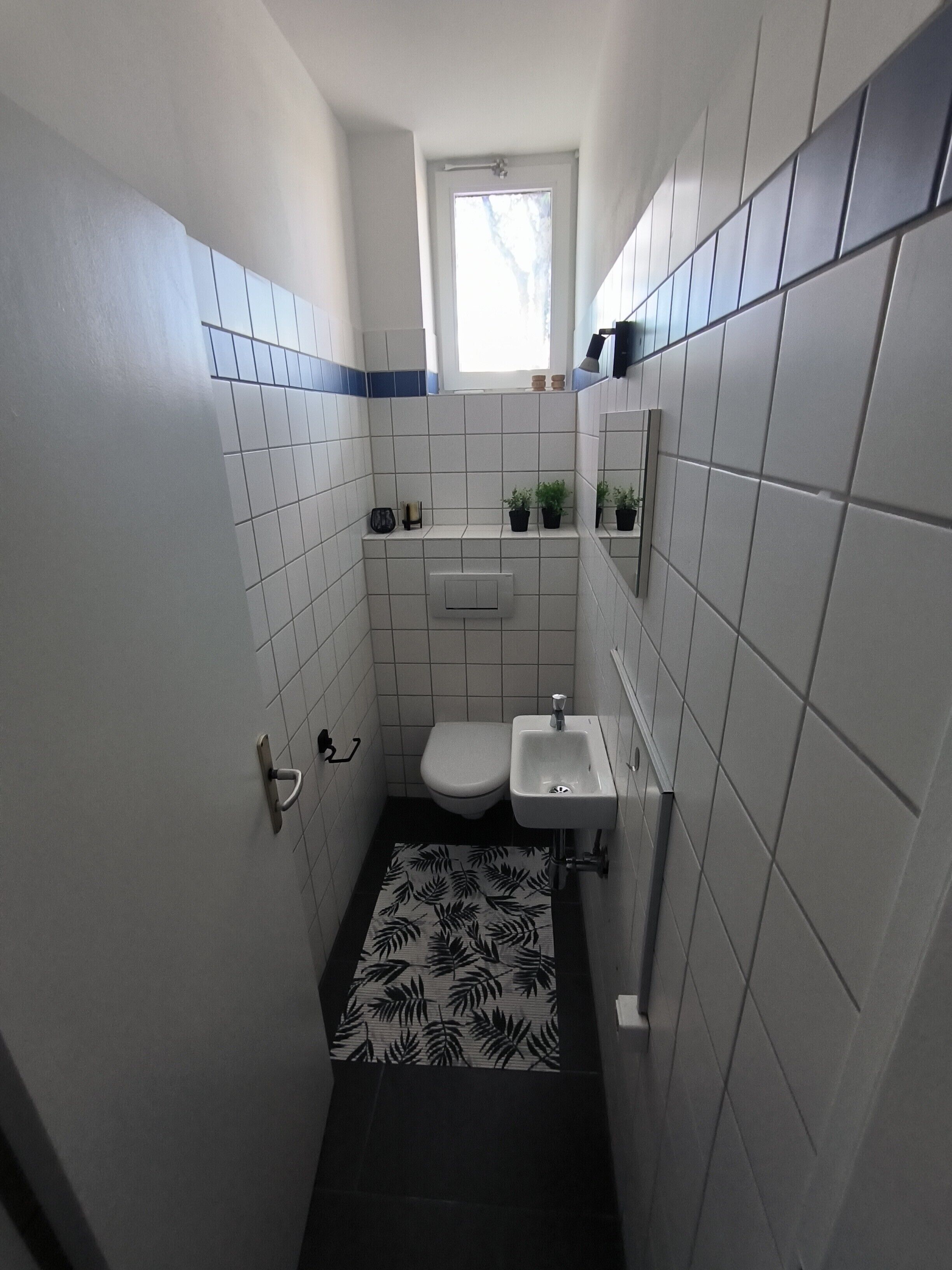 Un baño pequeño con inodoro, lavamanos y una ventana.