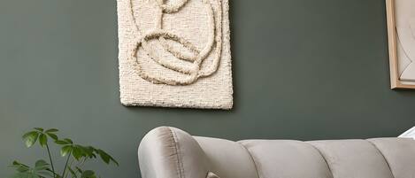 A room with a tufted sofa, a woven wall hanging, and a potted plant.