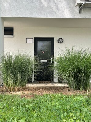 A modern building entrance with a black door, a welcome sign, and a small window.