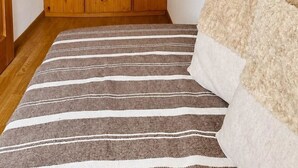 Una habitació amb un rug nétrajat, un armari de fusta i un quadre amb un cervel al mur.