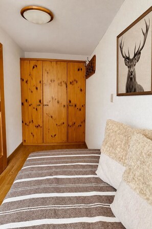 Ein Zimmer mit Streifenmuster-Teppich, einem Holzschrank und einem Bild von einem Reh an der Wand.