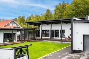 Ein modernes, zweistöckiges Haus mit überdachter Terrasse, gepflegtem Rasen und Garage.