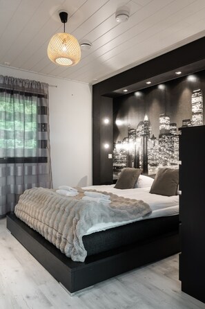 Ein modernes Schlafzimmer mit Stadtbild-Wandgemälde, einem großen Bett mit flauschiger Decke und einer hängenden Leuchte.
