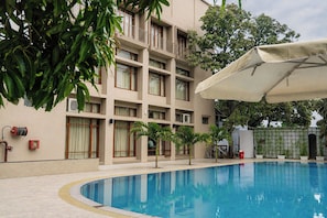 A hotel with a swimming pool, a covered outdoor area, and a multi-story building with balconies.
