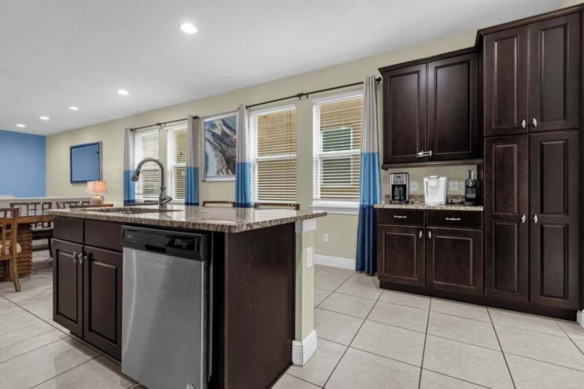 A kitchen with a central island, dark cabinetry, and a dishwasher.