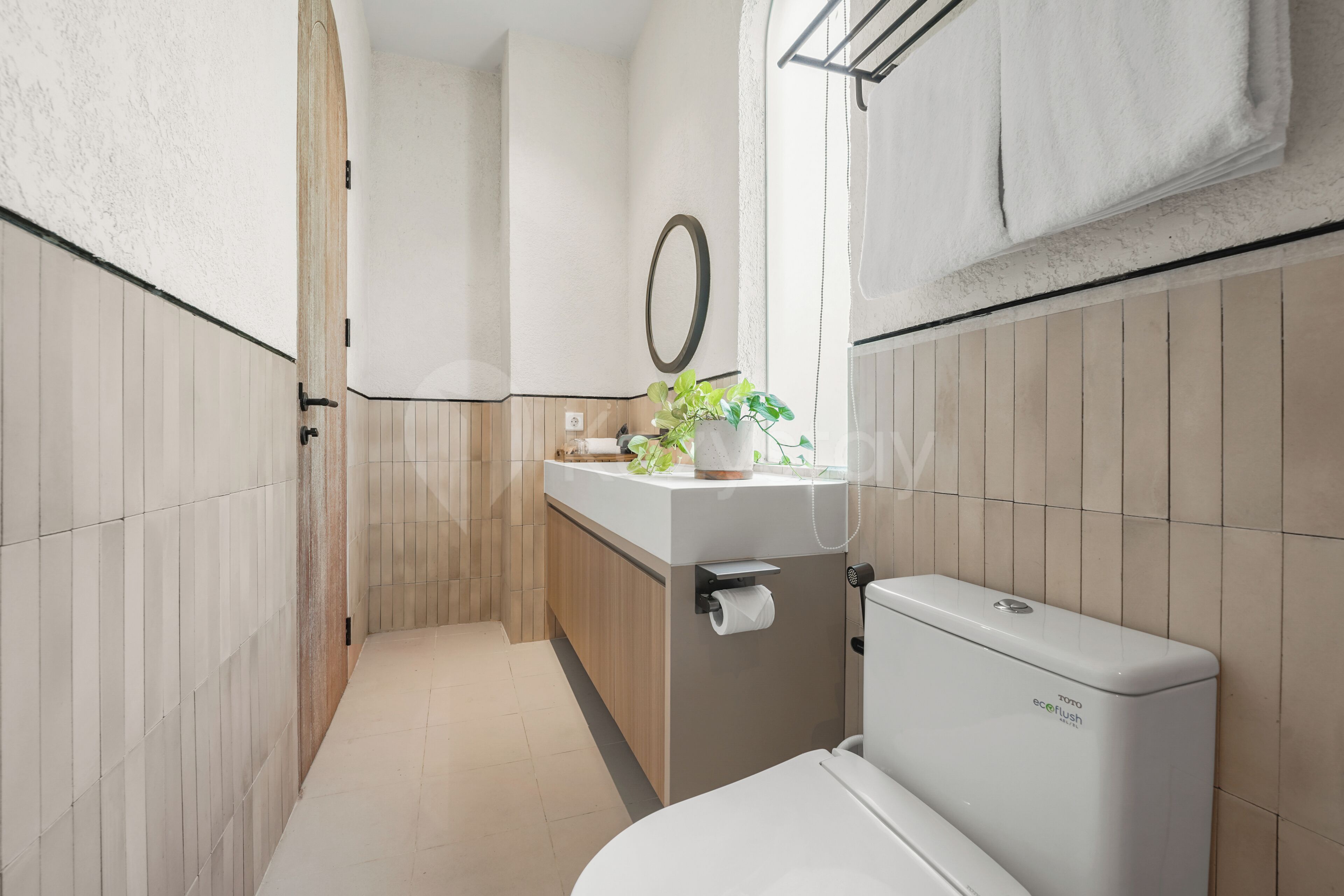 A compact bathroom with a toilet, sink, and a potted plant.