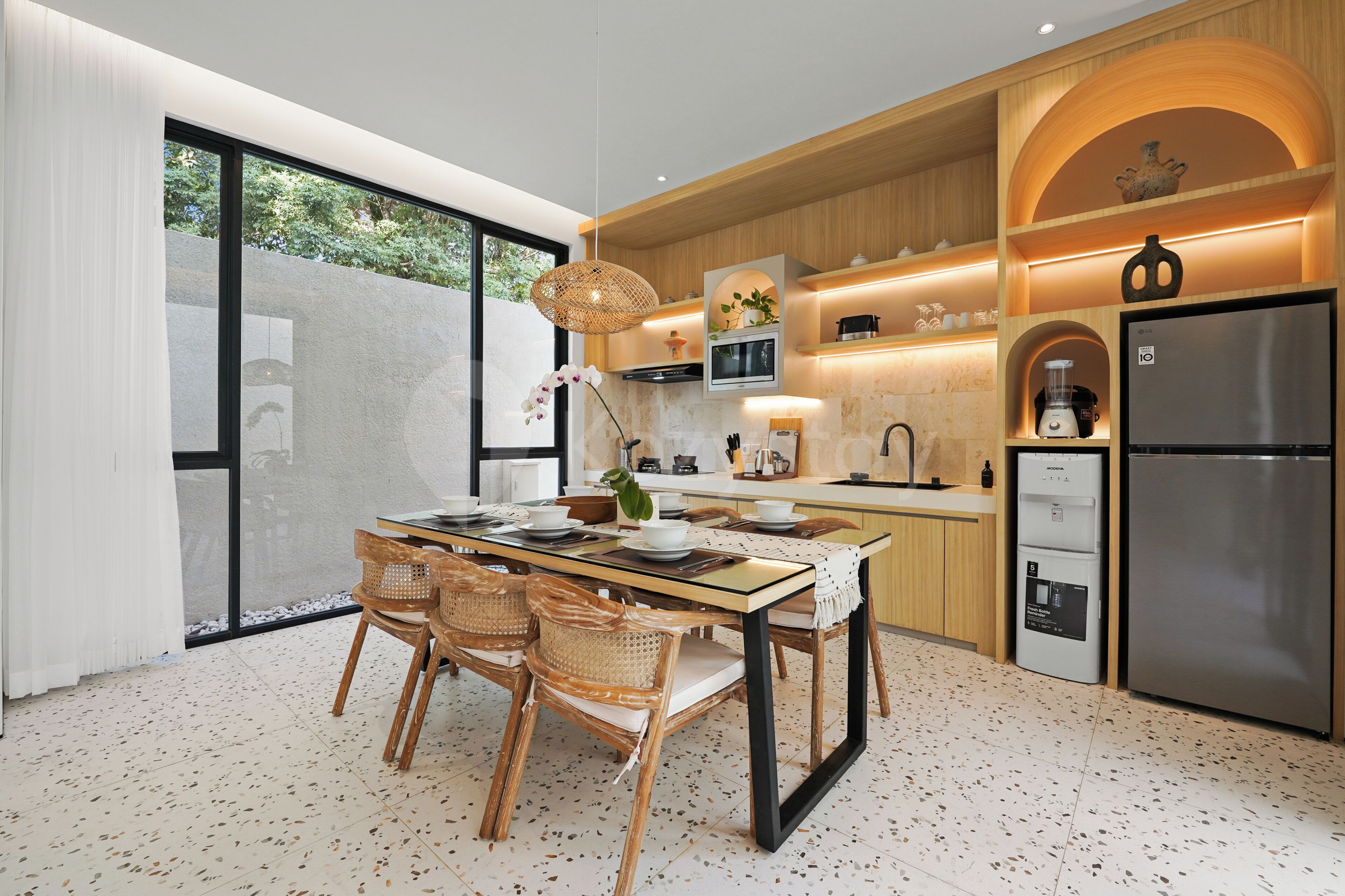 A modern kitchen with a dining area, featuring a large refrigerator, wooden cabinets, and a dining table with chairs.