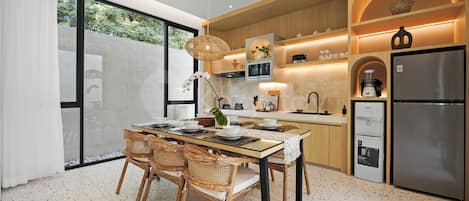 Una cocina moderna con comedor, que incluye un refrigerador grande, armarios de madera y una mesa de comedor con sillas.