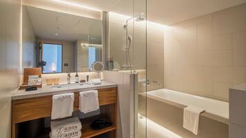 A modern bathroom with a glass-enclosed shower, a bathtub, and a vanity with a mirror and two sinks.