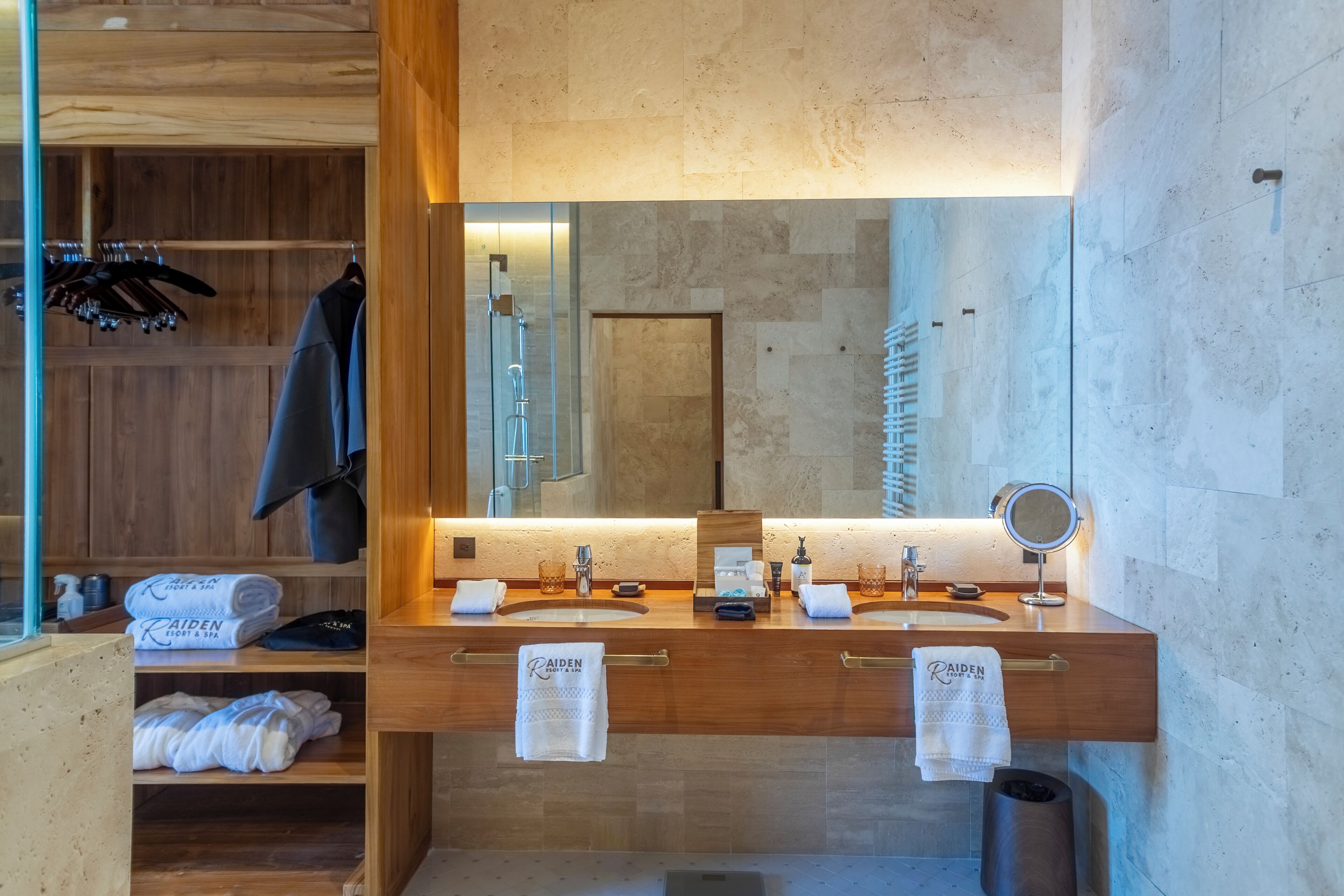 A modern bathroom with a wooden vanity, dual sinks, a large mirror, and a glass shower enclosure.