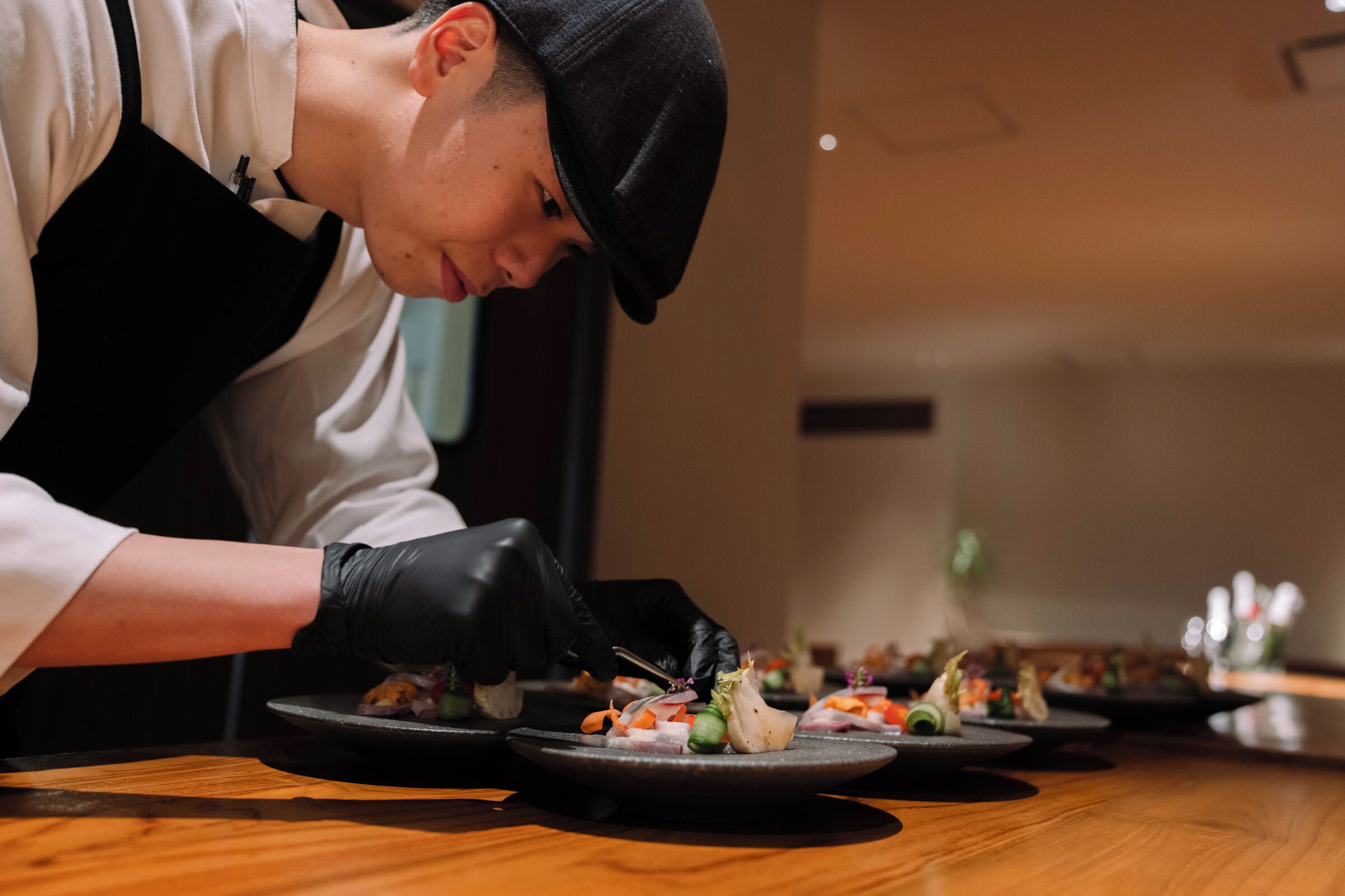 A person in a chef's uniform preparing food on a wooden table.