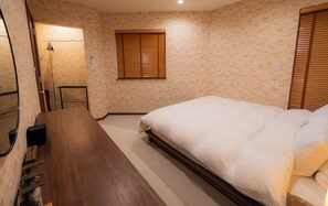 A hotel room with a wooden bed, a bedside table, a small desk, and a window with blinds. - *NEW OPEN* 4-minute walk to Ikebukuro Station | Japandi, 125 ㎡, 3 bedrooms | 9 guests | 5 minutes to Shinjuku (Nishiikebukuro Toshima-ku)