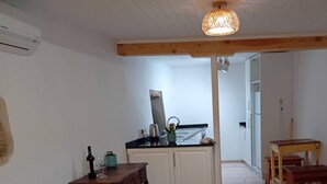 Quarto com cama, escrivaninha, cozinha compacta e vista para o exterior.