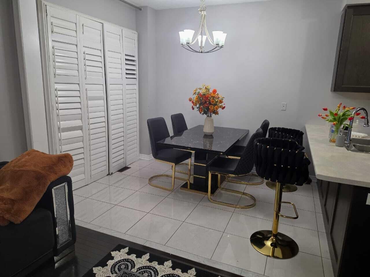 A dining area with a table and chairs, a chandelier, and a flower vase.