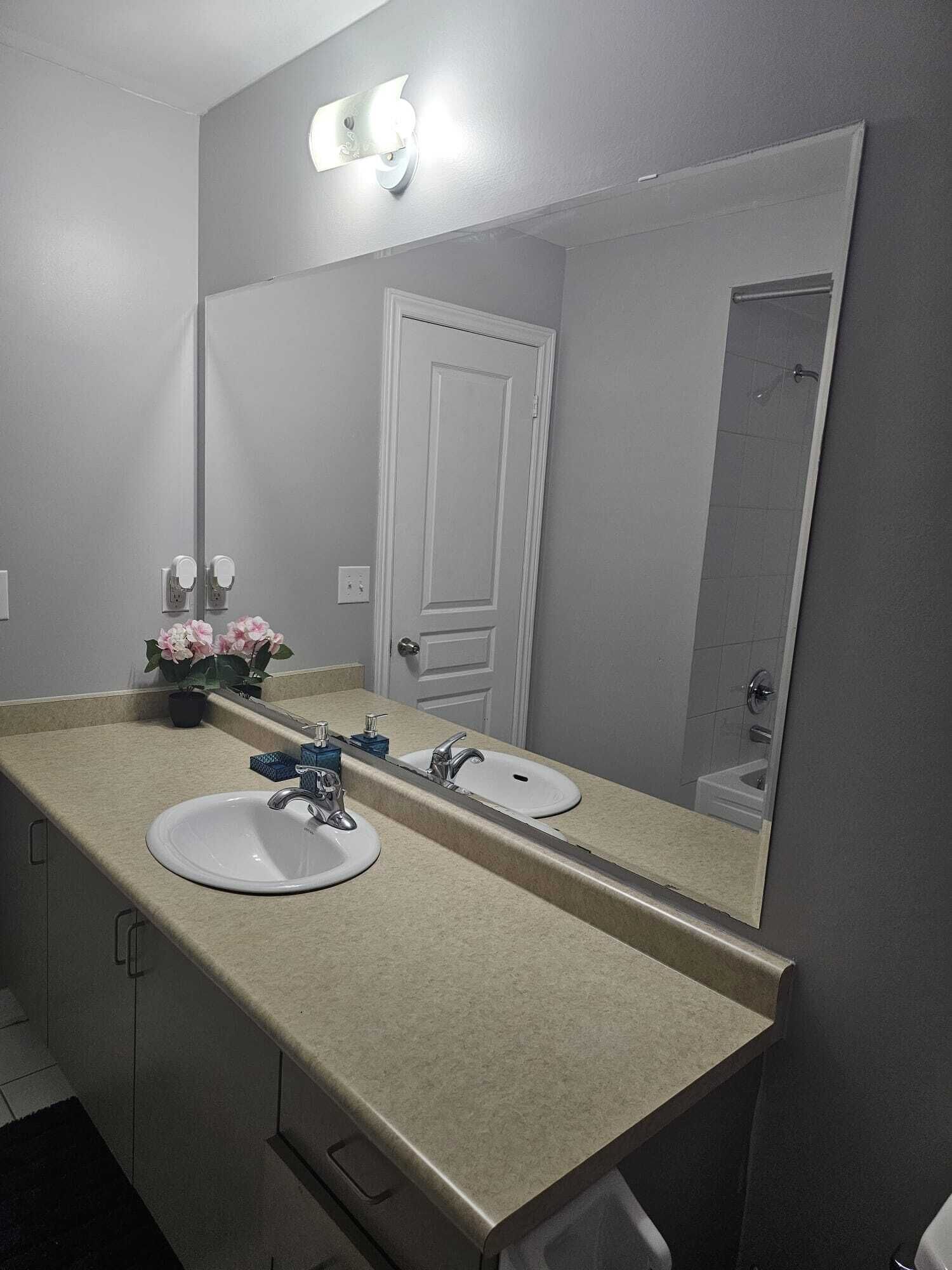 A bathroom with two sinks, a mirror, and a door.