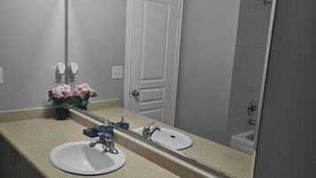 A bathroom with two sinks, a mirror, and a door.