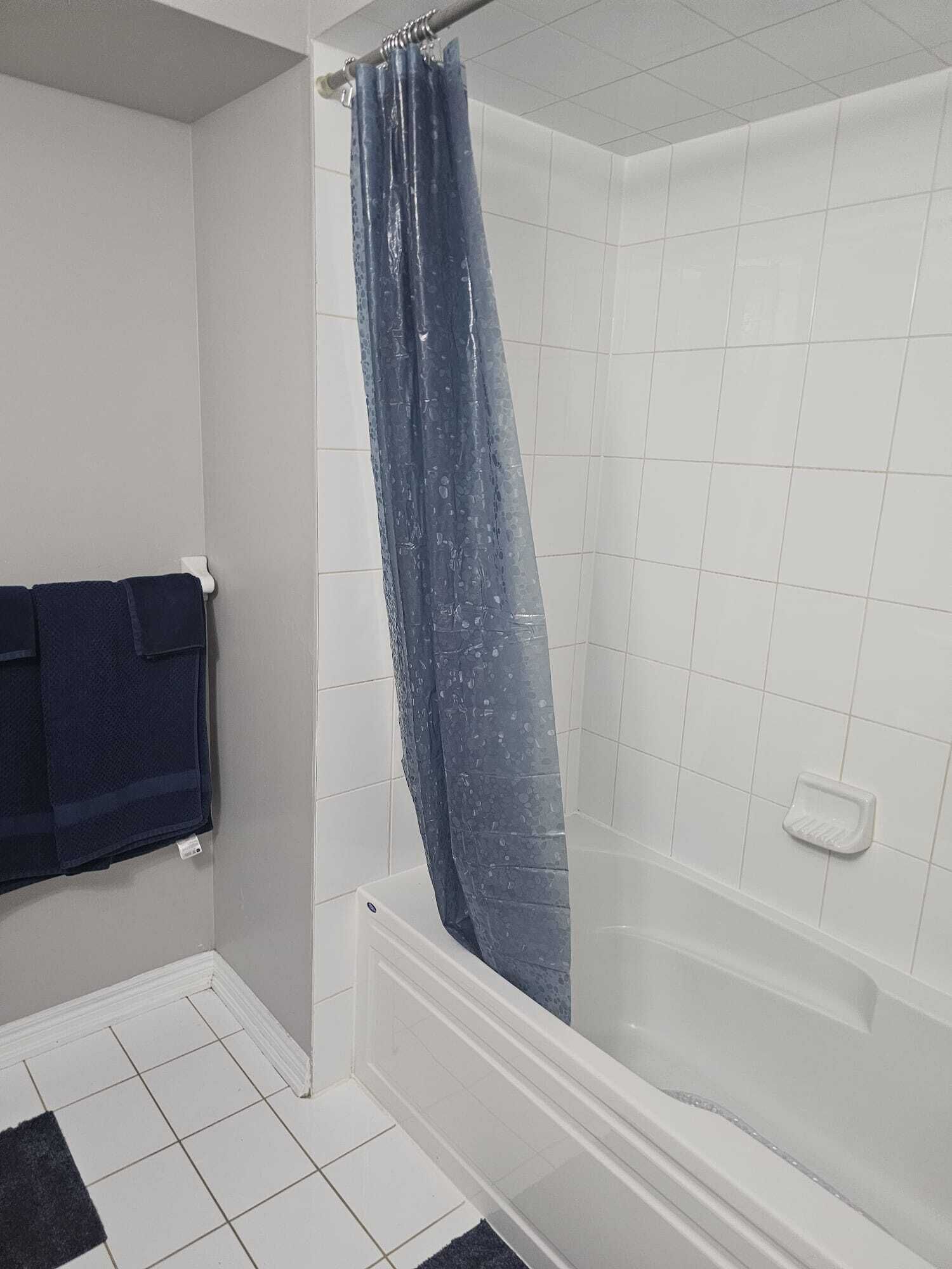 A bathroom with a shower curtain, a bathtub, and a towel rack.