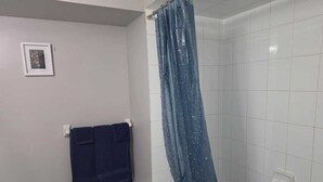 Een badkamer met een douche, een handdoekhouder en een foto aan de muur.