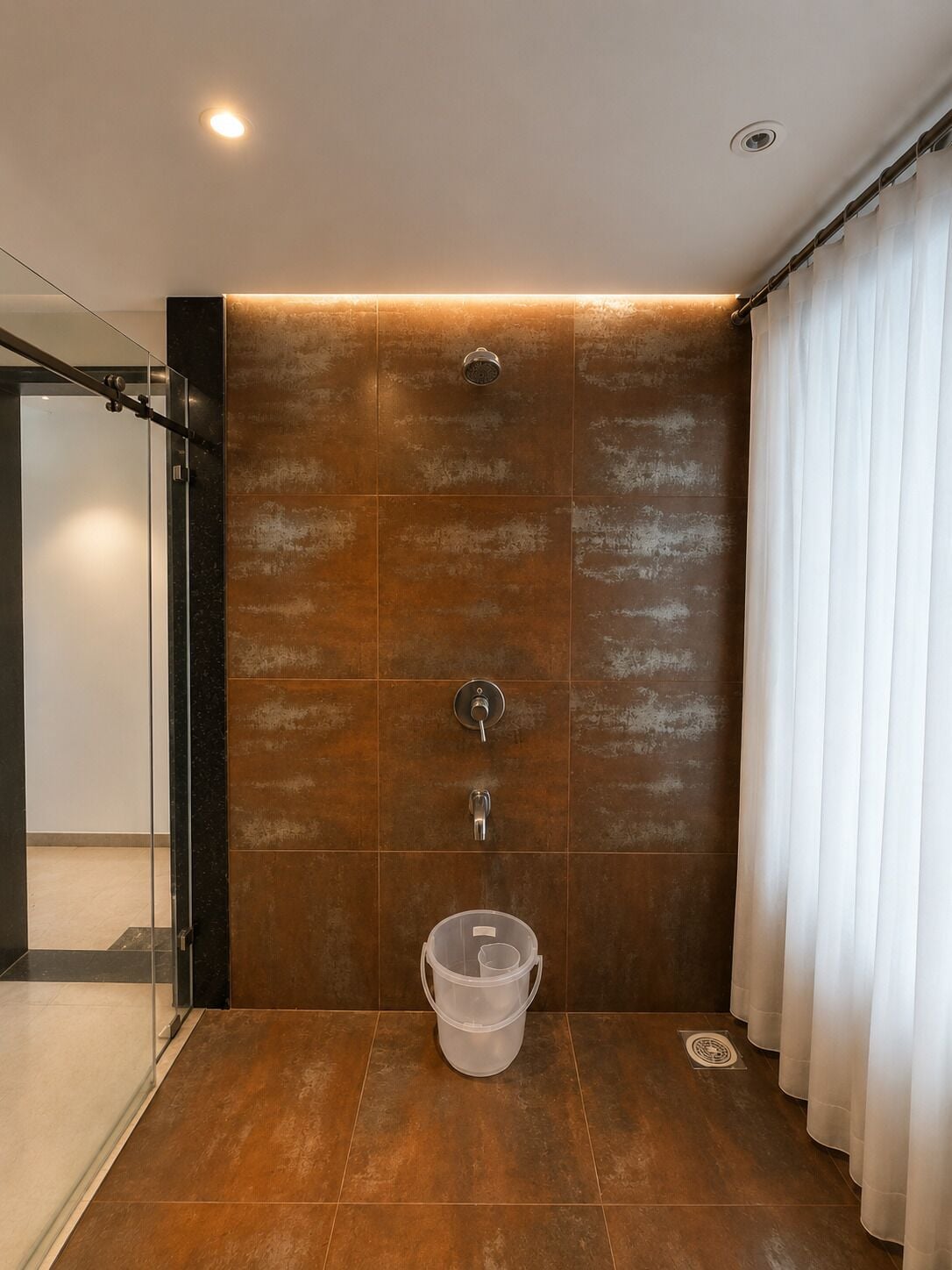 A modern bathroom with a shower, a glass door, and a white curtain.