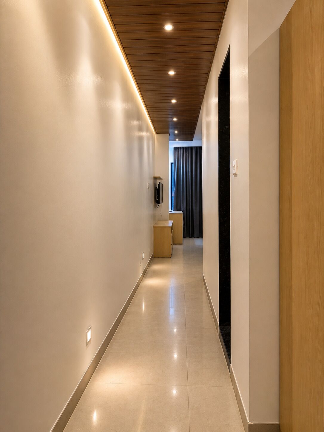 A modern hallway with a wooden ceiling, recessed lighting, and a flat floor.