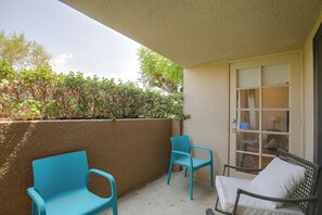 A balcony with two blue chairs and a wicker chair, a concrete wall, and a door with a security sign. - Unwind Poolside, Walk Dtwn! Palm Springs Retreat (Palm Springs)