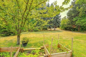 A garden with a wooden fence, a tree, and various plants.