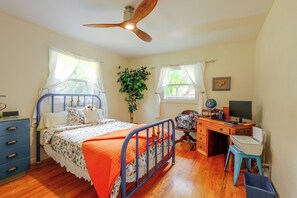 Ein Schlafzimmer mit einem Bett, Schreibtisch, Stuhl und Deckenventilator.