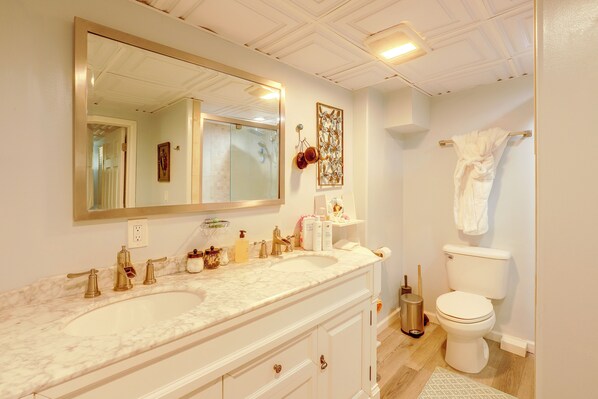A bathroom with a double vanity, a large mirror, a toilet, and a shower area. - The Habitat House: Retreat by Edgefield! (Troutdale)