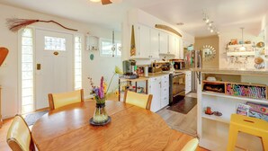 A kitchen with white cabinets, a dining table with chairs, and a variety of kitchen appliances. - The Habitat House: Retreat by Edgefield! (Troutdale)