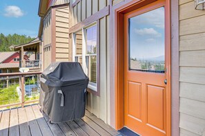 A wooden deck with a barbecue grill, a red door, and a view of a mountainous landscape. - Hike, Bike & Ski! Rendezvous Cabin w/ Mtn Views (Fraser)