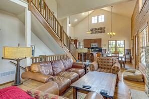 A spacious living room with a leather sofa, a coffee table, and a staircase leading to an upper level.