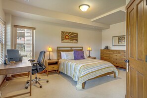 A bedroom with a bed, desk, chair, and two bedside lamps.