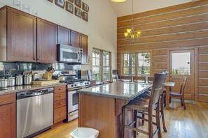 A kitchen with wooden cabinets, stainless steel appliances, and a large island with bar stools.