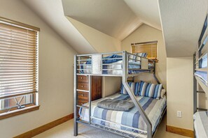A bunk bed room with a window and a built-in desk.
