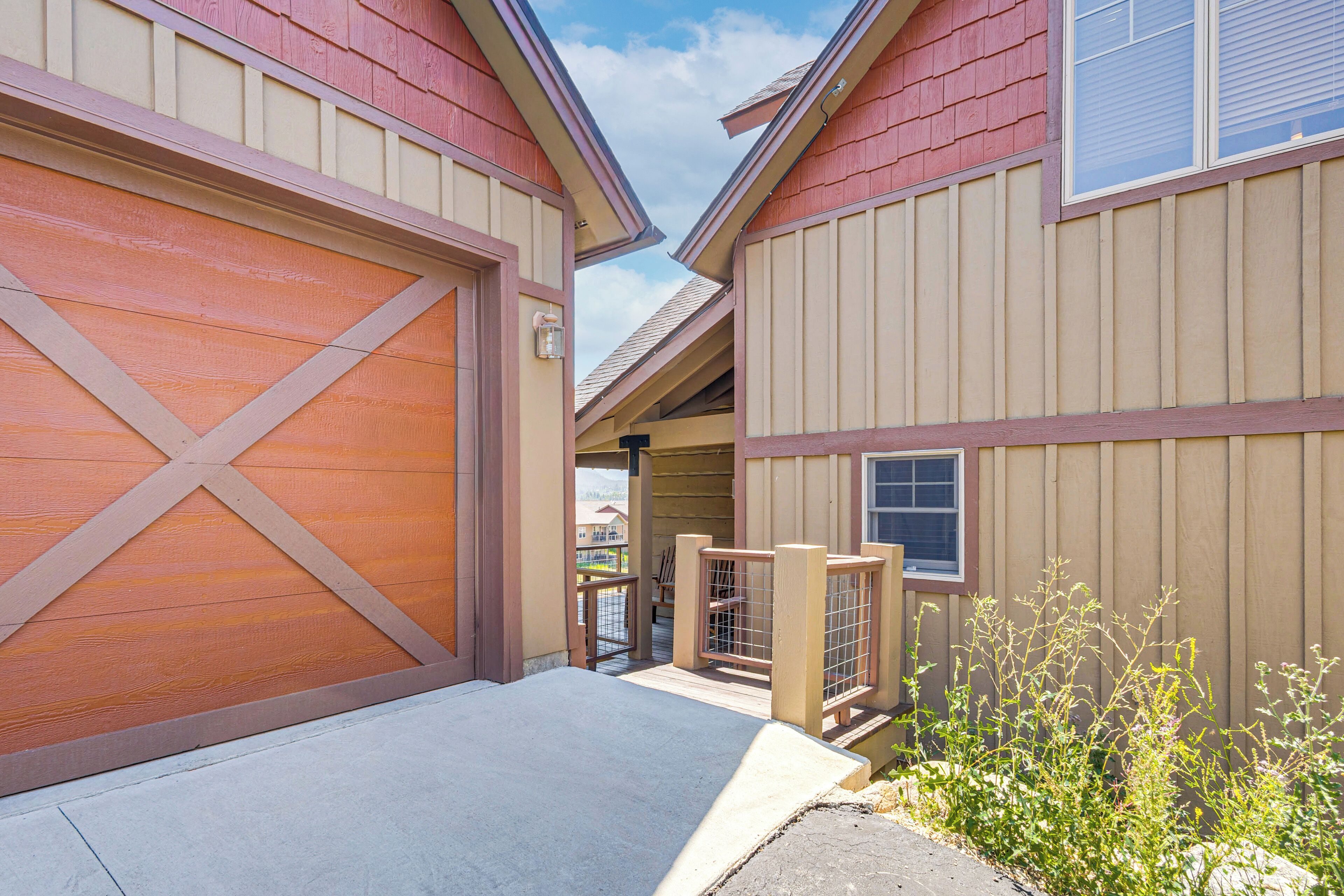 A residential building with a garage, a covered walkway, and a view of neighboring houses.