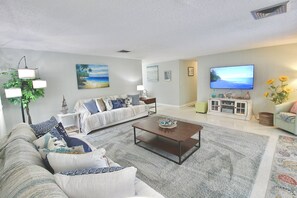 A living room with a sofa, a coffee table, and a television. - The Seaside Serenity at Thumb Point - Hutchinson Island - Prime Location - Pool Home! (Fort Pierce)