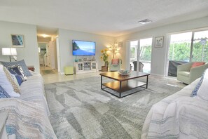A living room with a television, a coffee table, and a sofa. - The Seaside Serenity at Thumb Point - Hutchinson Island - Prime Location - Pool Home! (Fort Pierce)