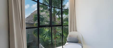 A room with a large window, a round table, and a chair.
