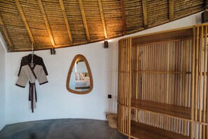 A room with a curved ceiling, a bed, a wardrobe with vertical slats, and a mirror on the wall. - Hillstone Luxury Villa 8 by Betterplace (Uluwatu)