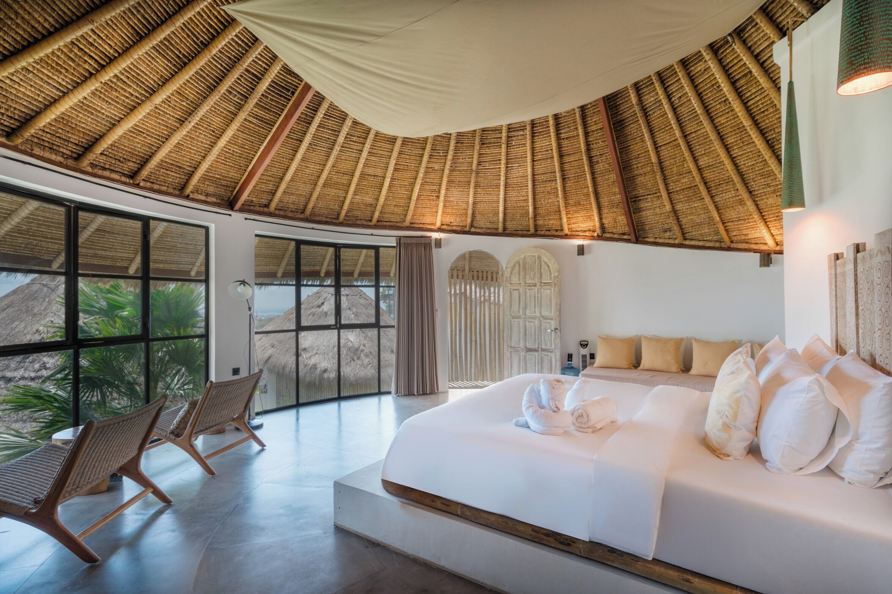 Une chambre à coucher avec un grand lit, une fenêtre et un toit de chaume.