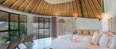 A bedroom with a large bed, a window, and a thatched roof.